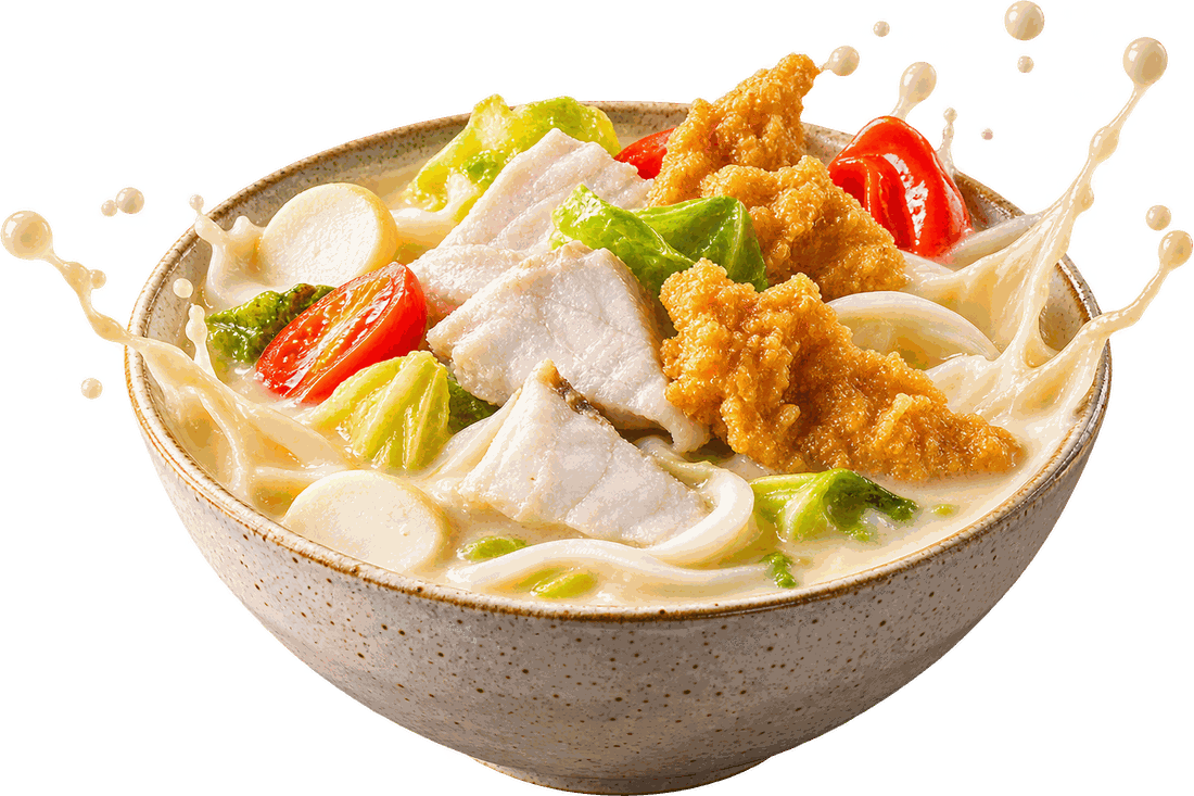 A bowl of Arcade fish soup made creamy with evaporated milk — sliced fish, fried fish, tofu, cabbage, tomato and thick beehoon, with milk splashing over the rim